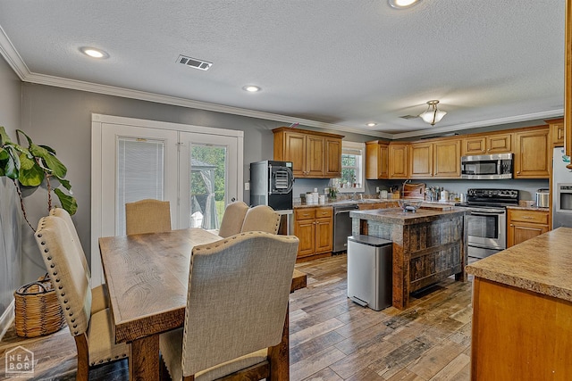 5010 S 28th St, Paragould, AR 72450 - kitchen featuring appliances with stainless steel finishes, crown molding, healthy amount of natural light, a textured ceiling, and light wood-style flooring