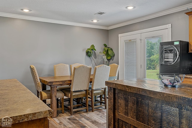 5010 S 28th St, Paragould, AR 72450 - dining space with crown molding, light wood-type flooring, a textured ceiling, recessed lighting, and stacked washing machine and dryer