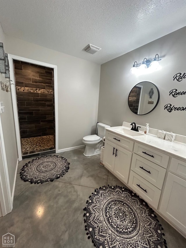 full bathroom with toilet, tiled shower, vanity, baseboards, and a textured ceiling