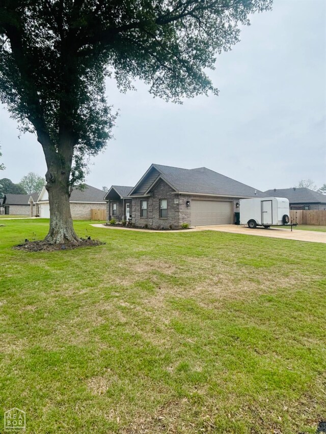 view of green lawn with concrete driveway and a garage