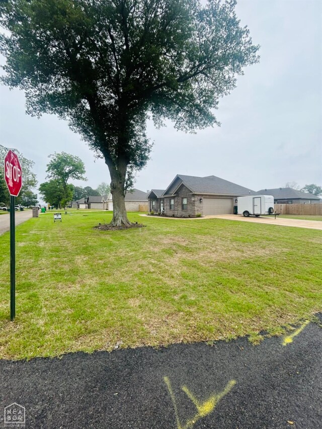 view of green lawn with an attached garage and driveway