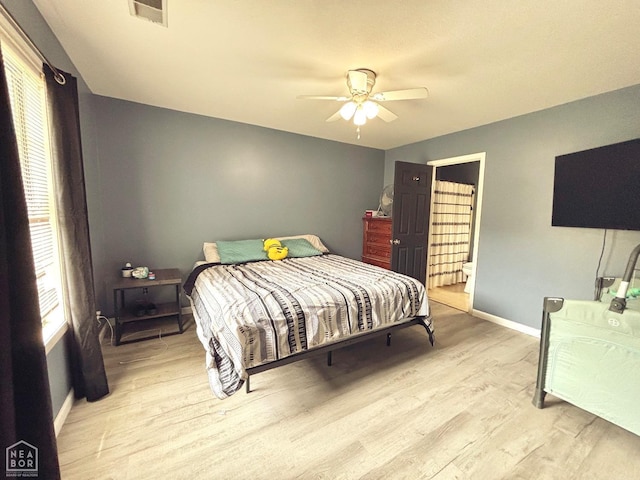 bedroom featuring visible vents, baseboards, ceiling fan, light wood-type flooring, and ensuite bath