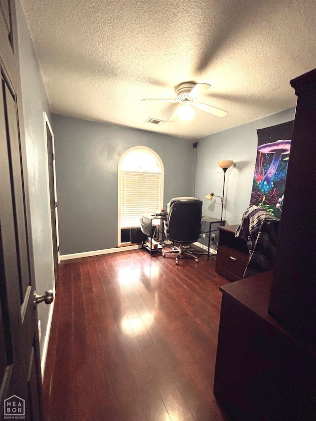 office space featuring ceiling fan, a textured ceiling, visible vents, dark wood finished floors, and baseboards