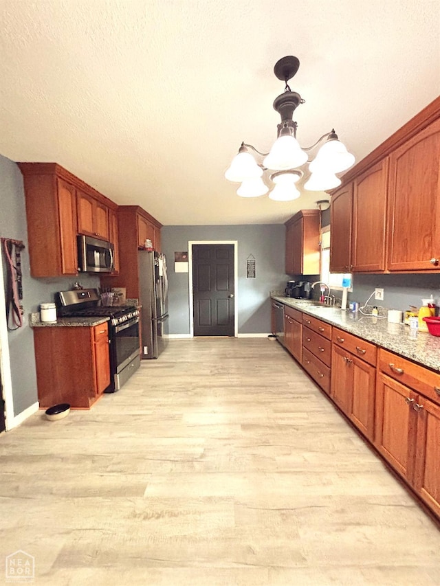 kitchen with baseboards, light wood-style flooring, appliances with stainless steel finishes, and a notable chandelier