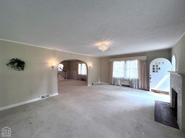 582 N 4th Ave, Piggott, AR 72454 - unfurnished living room with a textured ceiling, arched walkways, carpet flooring, baseboards, and a brick fireplace