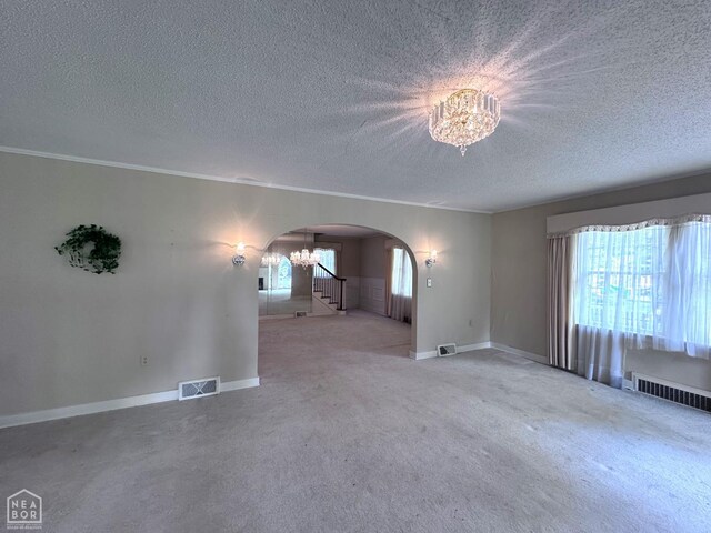 582 N 4th Ave, Piggott, AR 72454 - unfurnished living room featuring arched walkways, a chandelier, healthy amount of natural light, a textured ceiling, and carpet floors
