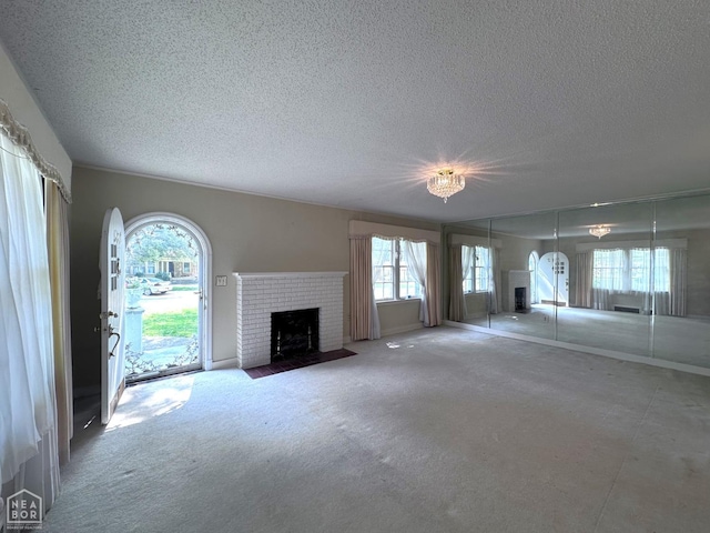 582 N 4th Ave, Piggott, AR 72454 - unfurnished living room featuring a fireplace, a textured ceiling, plenty of natural light, arched walkways, and carpet floors