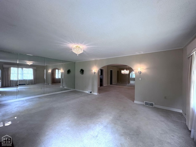 582 N 4th Ave, Piggott, AR 72454 - spare room featuring arched walkways, a textured ceiling, a chandelier, and baseboards