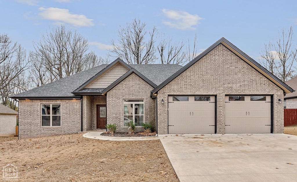 view of front of house featuring a shingled roof, brick siding, driveway, and an attached garage