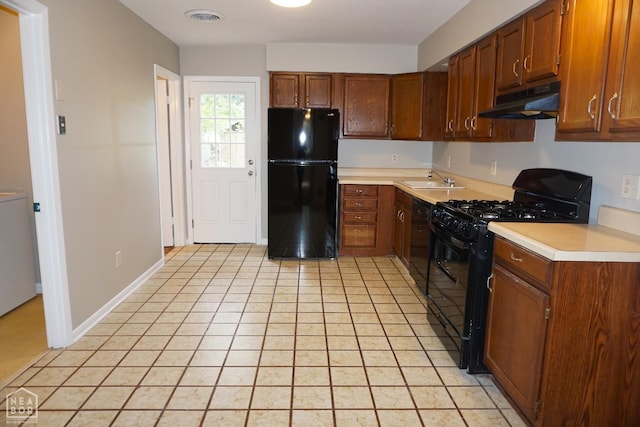 1805 Covey Dr, Jonesboro, AR 72404 - kitchen with black appliances, under cabinet range hood, light countertops, light tile patterned floors, and brown cabinets
