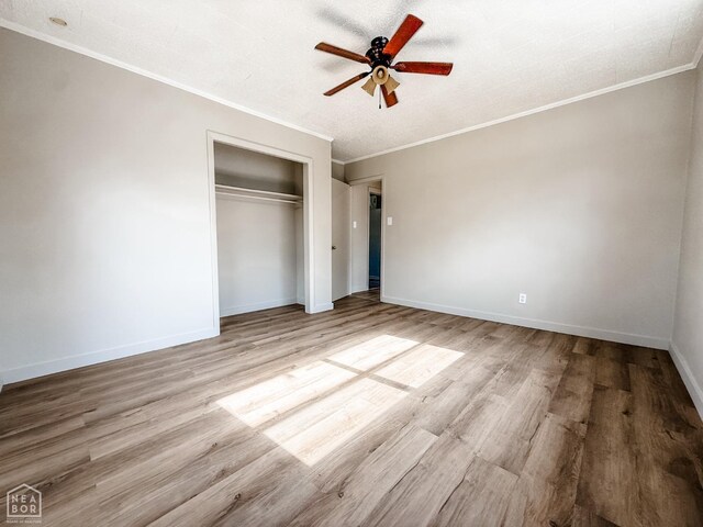 unfurnished bedroom with a closet, ornamental molding, and wood finished floors