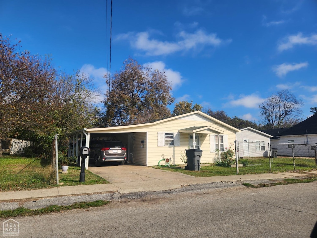 view of front facade with a front yard, fence, an attached carport, and driveway