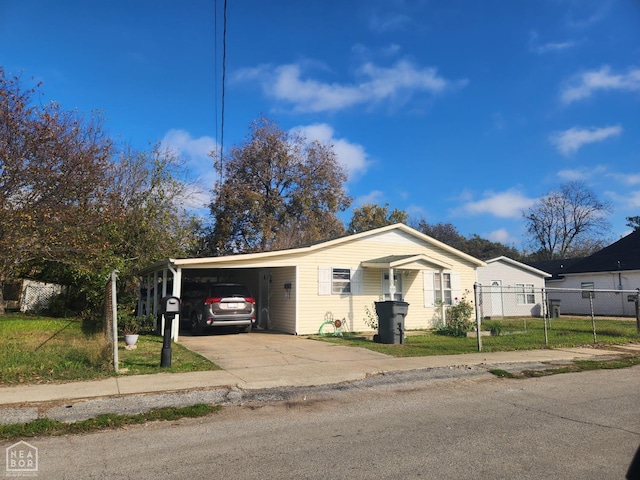 view of front facade with a front yard, fence, an attached carport, and driveway