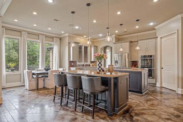 kitchen featuring a kitchen island with sink, stainless steel appliances, tasteful backsplash, and crown molding