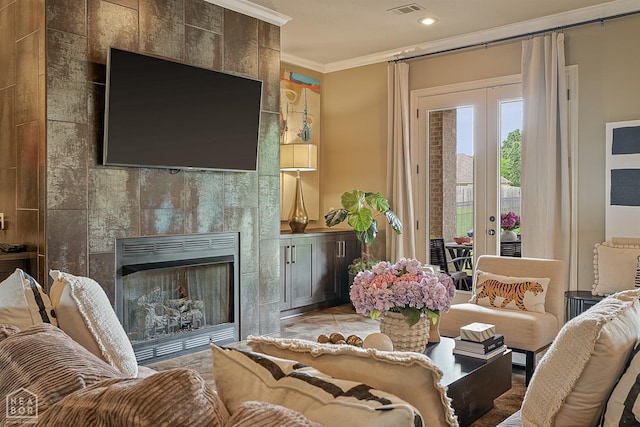living room with ornamental molding, french doors, a tiled fireplace, and recessed lighting