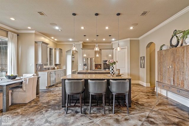 kitchen featuring a sink, a breakfast bar area, an island with sink, arched walkways, and appliances with stainless steel finishes