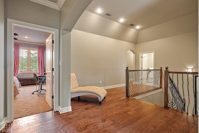 hallway with baseboards, visible vents, wood finished floors, arched walkways, and an upstairs landing