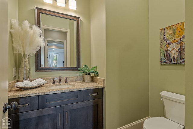 half bath with vanity, toilet, and baseboards