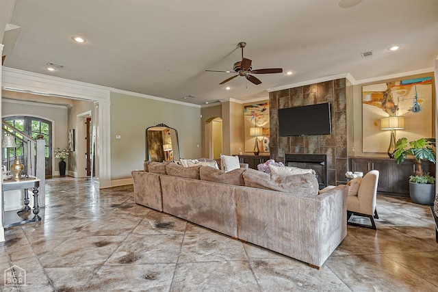 living area with a ceiling fan, recessed lighting, crown molding, arched walkways, and a fireplace