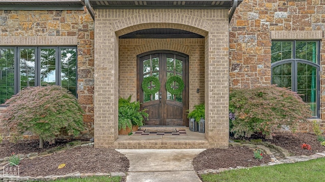 view of exterior entry with brick siding and french doors