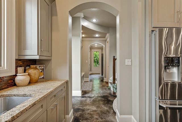 hall with a sink, finished concrete floors, ornamental molding, arched walkways, and baseboards