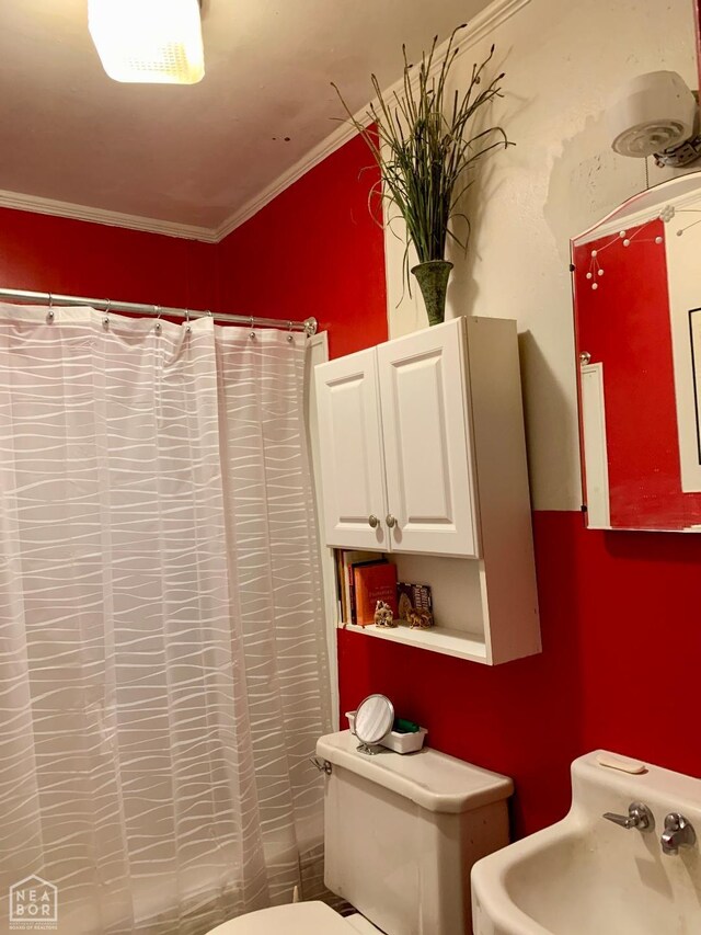 full bathroom with curtained shower, toilet, crown molding, and a sink