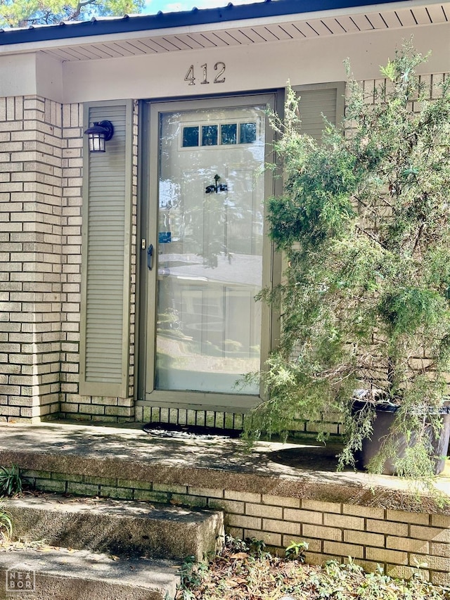 entrance to property featuring brick siding