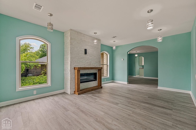 615 W Main St W, Trumann, AR 72472 - unfurnished living room featuring wood finished floors, baseboards, a stone fireplace, and arched walkways