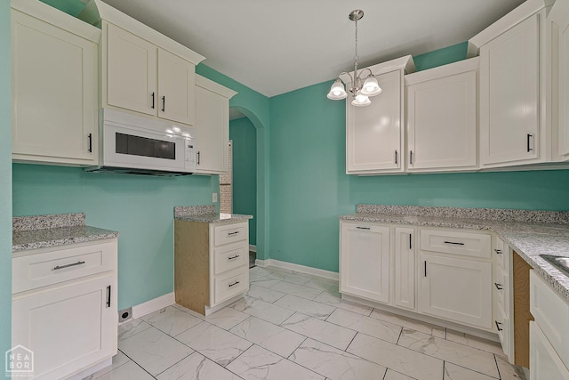 615 W Main St W, Trumann, AR 72472 - kitchen with white microwave, light marble finish floors, arched walkways, and baseboards