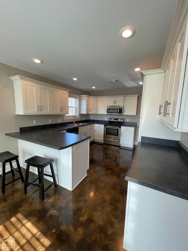 997 Russell Hill Dr, Jonesboro, AR 72404 - kitchen featuring a peninsula, white cabinets, dark countertops, a sink, and stainless steel appliances