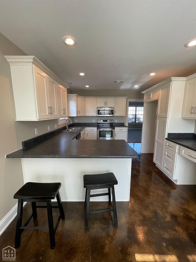 997 Russell Hill Dr, Jonesboro, AR 72404 - kitchen with stainless steel appliances, a peninsula, concrete floors, and dark countertops