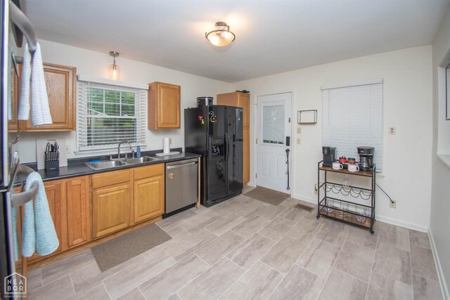 1123 Olive St, Jonesboro, AR 72401 - kitchen featuring dishwasher, black fridge with ice dispenser, a sink, dark countertops, and brown cabinets