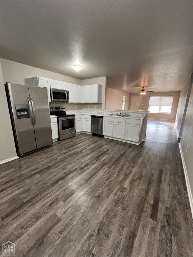 3804 Glitterman Dr, Jonesboro, AR 72404 - kitchen with appliances with stainless steel finishes, a peninsula, dark wood-style flooring, baseboards, and white cabinets