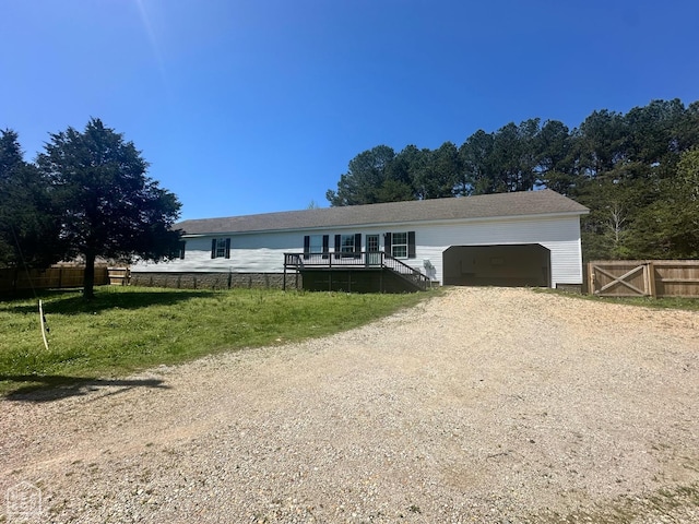 manufactured / mobile home with dirt driveway, an attached garage, and fence