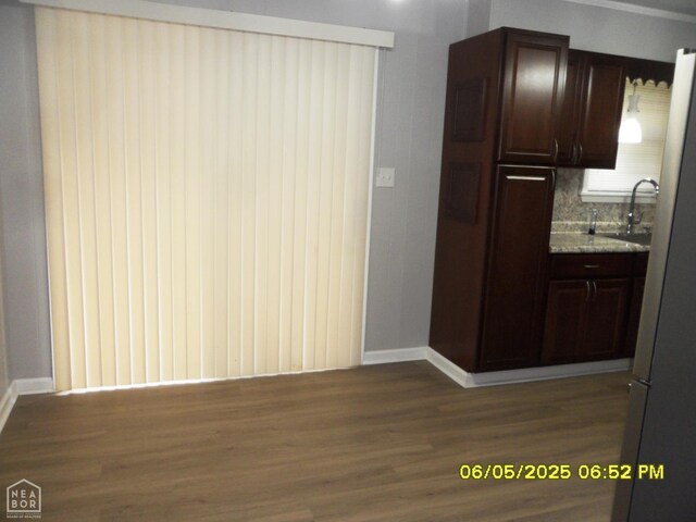 404 Logan St, Newport, AR 72112 - kitchen featuring dark brown cabinetry, dark wood finished floors, baseboards, a sink, and backsplash