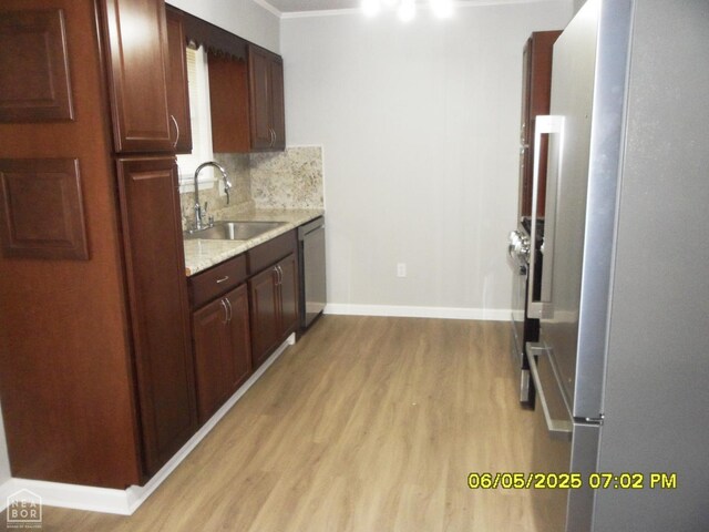 404 Logan St, Newport, AR 72112 - kitchen with appliances with stainless steel finishes, a sink, light wood-type flooring, decorative backsplash, and baseboards