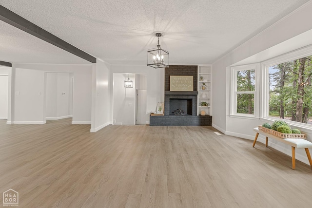 unfurnished living room with a chandelier, a textured ceiling, baseboards, and light wood-style flooring
