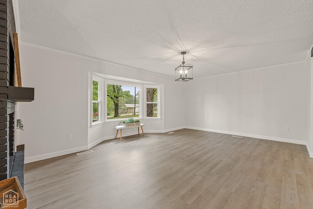 interior space featuring an inviting chandelier, visible vents, a textured ceiling, and wood finished floors