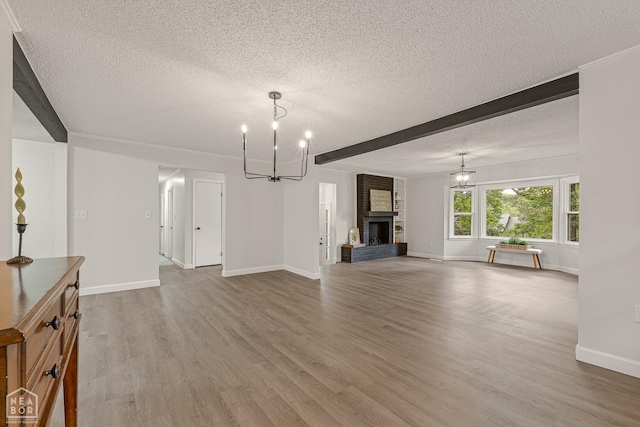 unfurnished living room featuring baseboards, a notable chandelier, a textured ceiling, and wood finished floors