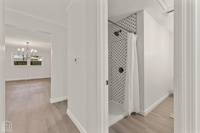 bathroom with a textured ceiling, wood finished floors, and a tile shower