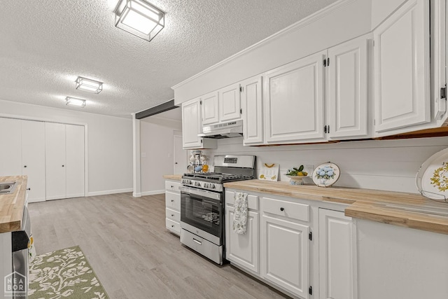 kitchen featuring butcher block countertops, a textured ceiling, under cabinet range hood, white cabinetry, and stainless steel range with gas stovetop