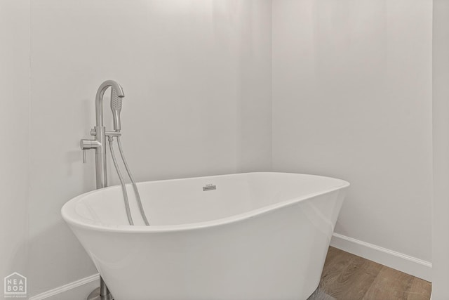 full bath with a soaking tub, wood finished floors, and baseboards