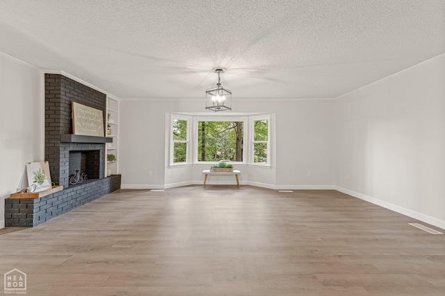unfurnished living room featuring a textured ceiling, wood finished floors, and a brick fireplace