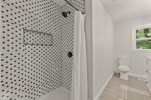 full bathroom featuring a textured ceiling, wood finished floors, and a tile shower