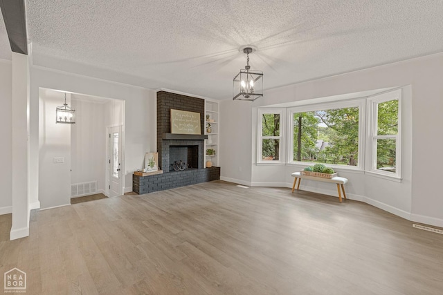 unfurnished living room featuring an inviting chandelier, visible vents, a textured ceiling, and wood finished floors