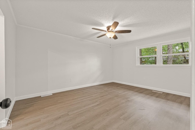 spare room with a textured ceiling, baseboards, visible vents, ceiling fan, and wood finished floors