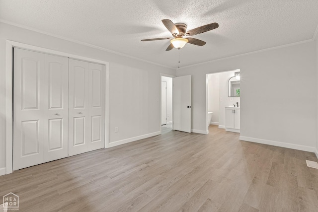 unfurnished bedroom featuring light wood finished floors, a closet, a textured ceiling, and ensuite bath