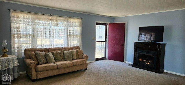 living room featuring a lit fireplace, baseboards, carpet, and ornamental molding