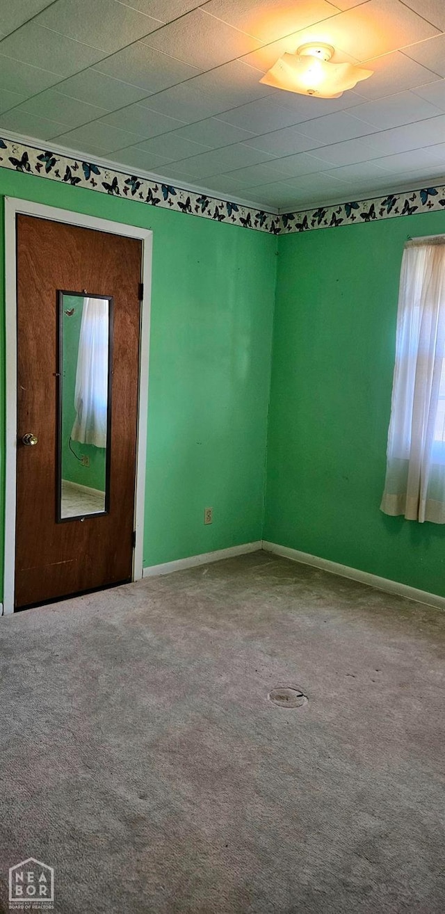 spare room with baseboards and carpet floors