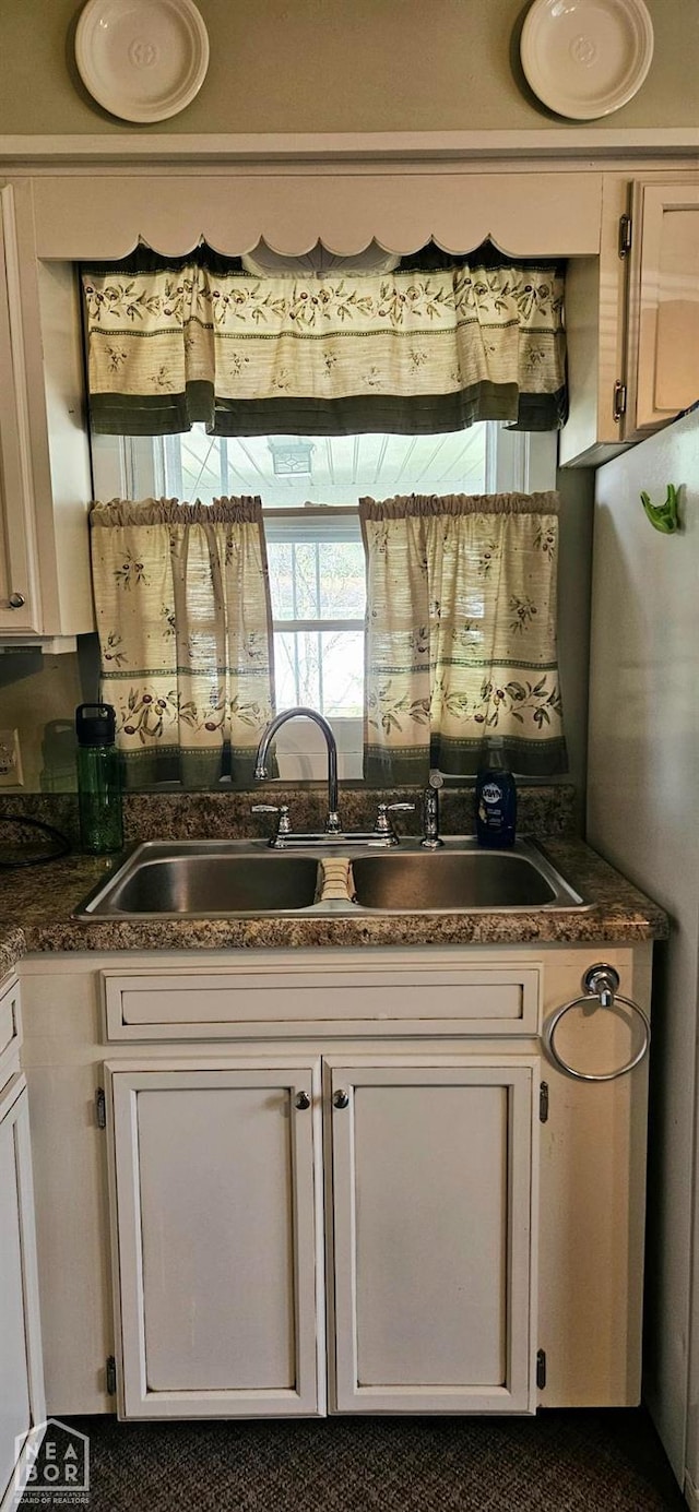 kitchen with white cabinets, dark countertops, and a sink